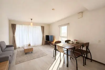 a living room with a table and chairs and a television at MUGI Stay 301 in Tokyo
