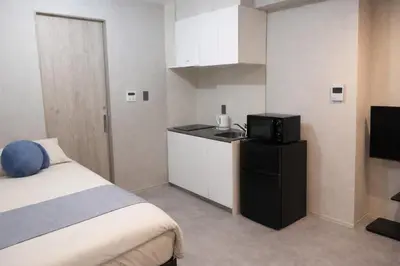 a room with a bed and a microwave and a kitchen at 201 Maison de Bohème Ryogoku in Tokyo