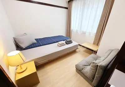 a small bedroom with a bed and a couch at Shinmei Tokyo Omori in Tokyo