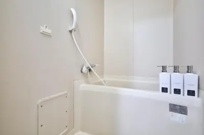 a white bathroom with a tub and a toilet at \u30a8\u30de\u30fc\u30ec\u6771\u5c0f\u5ca9205 \u5c0f\u5ca9\u99c5\u5f92\u6b695\u5206 \u6700\u59275\u540d \u548c\u5ba4\u7573 in Tokyo