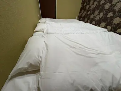 an unmade bed with white sheets in a room at EASE Shinjuku in Tokyo