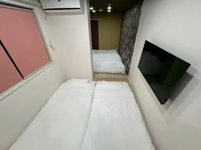 a small room with two beds and a flat screen tv at EASE Shinjuku in Tokyo