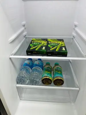 a refrigerator with bottles of water in a drawer at Shimokitazawa Cozy Apartment 202 in Tokyo