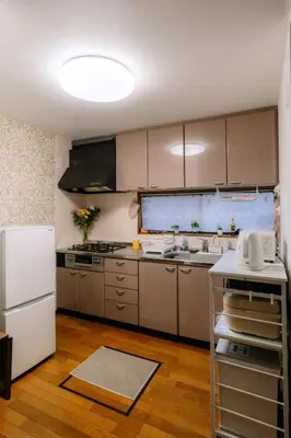 a kitchen with brown cabinets and a white refrigerator at Kimiko Jujo House - Local Art Stay 11 min Shinjuku in Tokyo