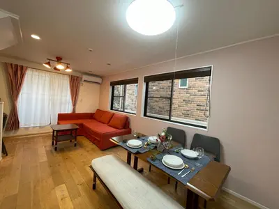a living room with a table and a red couch at Prime Shinjuku - 12min to Kabukicho - Quiet Park Area - Entire House - 3BD 6Beds - 70 sqm 750 sqft in Tokyo