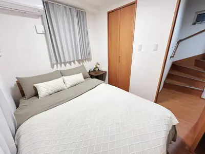 a bedroom with a large bed and a staircase at Newly built house with free parking, 3 minutes walk from Shinkoiwa Station in Tokyo
