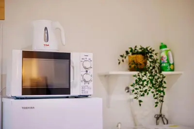 a microwave sitting on top of a refrigerator at M101 5-minute walk from Minowa Station on the Hibiya Line, straight to Ueno, Akihabara, Ginza in Tokyo