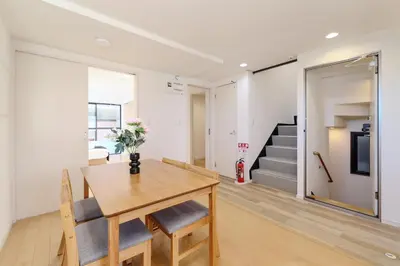 a dining room with a table and chairs and a staircase at ohayo\u5c0f\u5c71\u53f0 in Tokyo