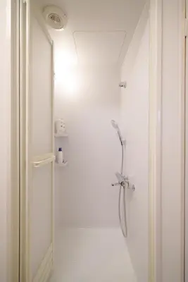 a white bathroom with a shower with a glass door at ohayo\u5c0f\u5c71\u53f0 in Tokyo
