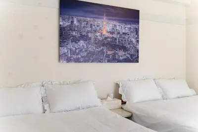a bedroom with two beds and a painting on the wall at SHINBASHI Station A major hub station ideal for Tokyo sightseeing Numerous restaurants and eateries surround the station Enjoy your stay on the top floor of the building without worrying about noise Elevator available in Tokyo