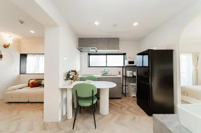 a kitchen and living room with a white table and green chairs at C1 Shibuya, 2 bedrooms and 1 living room 2 bathrooms 2 toilets, 7 mins to ST Max 6P \u6e0b\u8c37\u5168\u65b0\u88c5\u4fee \u4e24\u5ba4\u4e00\u5385 \u4ea4\u901a\u4e2d\u5fc3 \u8f66\u7ad97\u5206\u949f \u6700\u59276\u4eba \u76f4\u8fbe\u65b0\u5bbf \u6d89\u8c37 \u8868\u53c2\u9053 \u54c1\u5ddd \u6c60\u888b \u4e0a\u91ce \u4ee3\u4ee3\u6728 \u94f6\u5ea7 \u539f\u5bbf in Tokyo