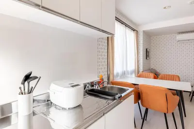 a kitchen with a sink and a counter with orange chairs at \u6d45\u8349\u30de\u30a4\u30db\u30c6\u30eb Asakusa My apartment Hotel in Tokyo