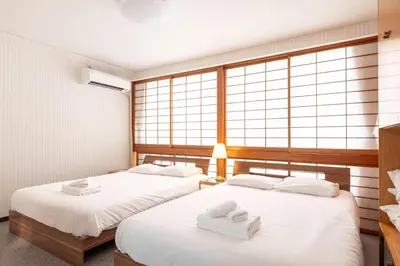 two beds in a room with large windows at \u6d45\u8349\u30de\u30a4\u30db\u30c6\u30eb Asakusa My apartment Hotel in Tokyo