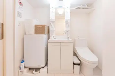 a white bathroom with a toilet and a sink at Crecer Apartment Hotel kamata in Tokyo