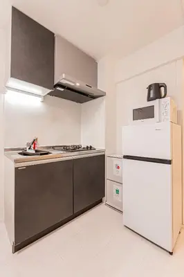 a kitchen with a white refrigerator and a stove at Crecer Apartment Hotel kamata in Tokyo
