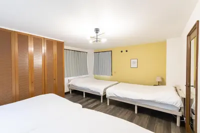 two beds in a room with wooden cabinets at Kotori Ayase in Tokyo
