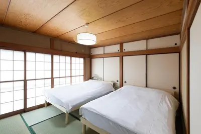 two beds in a room with wooden ceilings and windows at Kotori Ayase in Tokyo