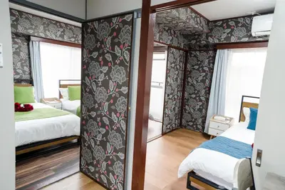 a bedroom with two beds and a wall with floral wallpaper at 201Room 1 Stop from Ikebukuro Entire 33m on 2st Floor 2 Bedrooms for up to 6 Guests 3Minute Walk to Don Quijote in Tokyo