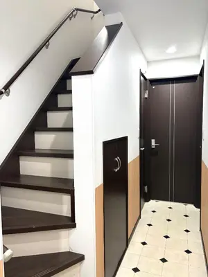 a hallway with stairs and a black door at sakura\u306e\u5bb6 in Tokyo