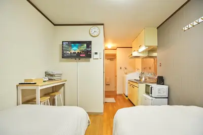 a small room with two beds and a clock on the wall at \u65b0\u5bbf\u5e02\u4e2d\u5fc3\u6771\u65b0\u5bbf\u7ad9\u5f92\u6b653\u5206\u937e\u6b4c\u821e\u4f0e\u753a\u7d27\u90bb\u4f0a\u52bf\u4e39\u767e\u8d27#12 in Tokyo