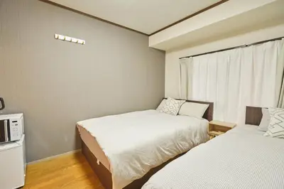 a small room with two beds and a window at \u65b0\u5bbf\u5e02\u4e2d\u5fc3\u6771\u65b0\u5bbf\u7ad9\u5f92\u6b653\u5206\u937e\u6b4c\u821e\u4f0e\u753a\u7d27\u90bb\u4f0a\u52bf\u4e39\u767e\u8d27#12 in Tokyo