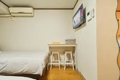 a bedroom with a bed and a desk with two stools at \u65b0\u5bbf\u5e02\u4e2d\u5fc3\u6771\u65b0\u5bbf\u7ad9\u5f92\u6b653\u5206\u937e\u6b4c\u821e\u4f0e\u753a\u7d27\u90bb\u4f0a\u52bf\u4e39\u767e\u8d27#12 in Tokyo