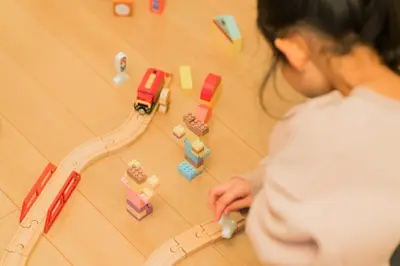 a woman playing with a toy train on the floor at MaiMai Yahiro in Tokyo