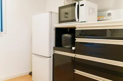 a kitchen with a microwave and a refrigerator at MaiMai Yahiro in Tokyo