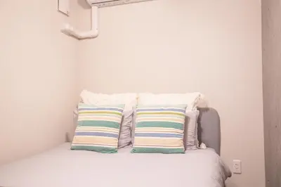 a white bed with two pillows on top of it at \u4e0a\u91ce\u6d45\u8349\u30a8\u30ea\u30a2\u597d\u30a2\u30af\u30bb\u30b9 \u4ea4\u901a\u81f3\u4fbf \u89b3\u5149 \u30b7\u30e7\u30c3\u30d4\u30f3\u30b0 \u30b0\u30eb\u30e1\u306b\u6700\u9069\u306a\u6771\u4e0a\u91ce\u306e\u5bbf YoYh in Tokyo