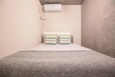 a small bedroom with a bed with two pillows at \u4e0a\u91ce\u6d45\u8349\u30a8\u30ea\u30a2\u597d\u30a2\u30af\u30bb\u30b9 \u4ea4\u901a\u81f3\u4fbf \u89b3\u5149 \u30b7\u30e7\u30c3\u30d4\u30f3\u30b0 \u30b0\u30eb\u30e1\u306b\u6700\u9069\u306a\u6771\u4e0a\u91ce\u306e\u5bbf YoYh in Tokyo