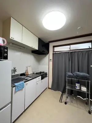 a small kitchen with white cabinets and a refrigerator at Abeno house at Koenji in Tokyo