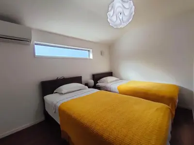two beds in a room with yellow sheets at SunRiseStay Yahiro House\u516b\u5e83\u4e00\u6238\u5efa\u3066 in Tokyo