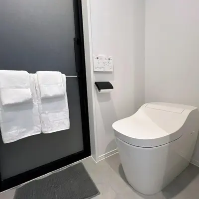 a bathroom with a white toilet and towels at KICHI 2F 10min to Shinjuku in Tokyo