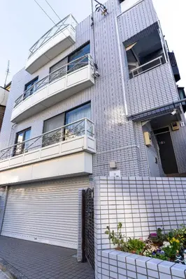 a white brick building with a balcony at Crest House in Tokyo