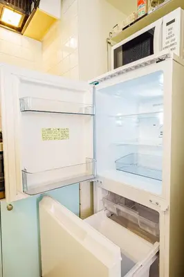 an empty refrigerator with its door open in a kitchen at Crest House in Tokyo