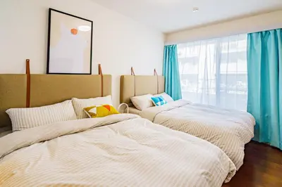 two beds in a bedroom with blue curtains at Crest House in Tokyo