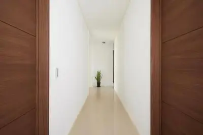 a hallway with white walls and a wooden door at Yamatsu Tokyo House in Tokyo