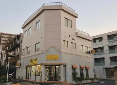 a tall white building with a store front at Yamatsu Tokyo House in Tokyo