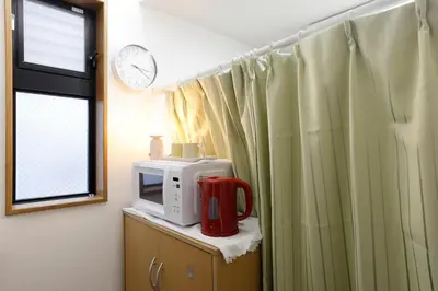 a kitchen with a microwave and a clock on the wall at 3 min from Shin-Okubo l Private Single Room 4 in Tokyo