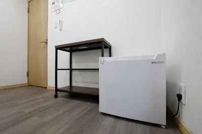 a room with a bed and a refrigerator next to a wall at Tokyo My Home 201 in Tokyo