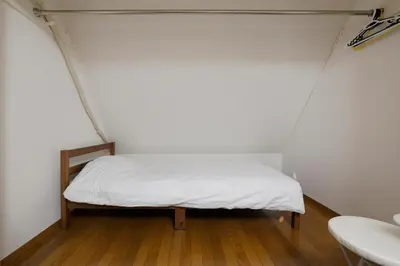 a small bed in a small room with white sheets at 3 min from Shin-Okubo l Private Family Room for 5 in Tokyo