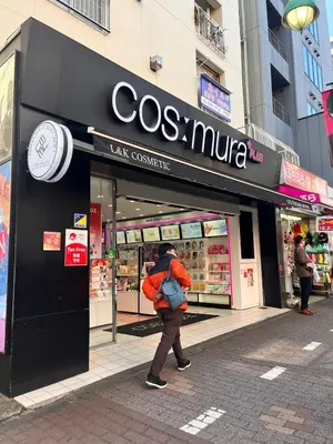 a person walking in front of a store at 3 min from Shin-Okubo l Private Family Room for 5 in Tokyo