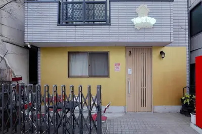 a yellow building with a fence in front of it at 3 min from Shin-Okubo l Family Room for 4 in Tokyo