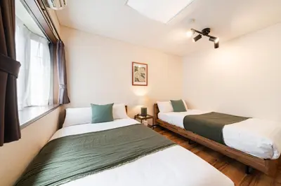 two beds in a small room with a window at HOTEL AndPlace ShinOkubo in Tokyo