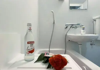 a bottle of alcohol and a flower on a bathroom counter at Mando Hotel 301 ,direct to Ueno ,Asakusa in Tokyo
