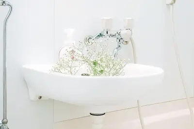 a white sink with flowers in it in a bathroom at Mando Hotel 301 ,direct to Ueno ,Asakusa in Tokyo