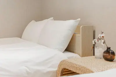 a bed with white sheets and a pillow and a table at \u4e09\u8ed2\u8336\u5c4bCasa Blanky in Tokyo