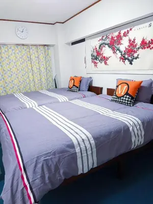 two twin beds in a room with a picture on the wall at Kabuki house in Tokyo