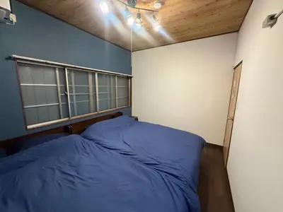 a bedroom with a blue bed and a window at \u307b\u307e\u308c\u53e4\u6c11\u5bb6\u4e00\u68df\u8cb8\u3057\u65b0\u5c0f\u5ca9\u99c5\u5f92\u6b6917\u5206 in Tokyo