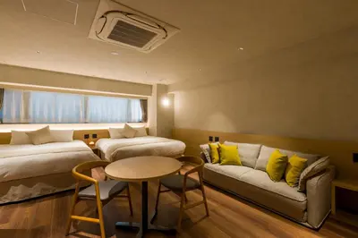 a room with two beds and a couch and a table at Sumu Ueno East in Tokyo